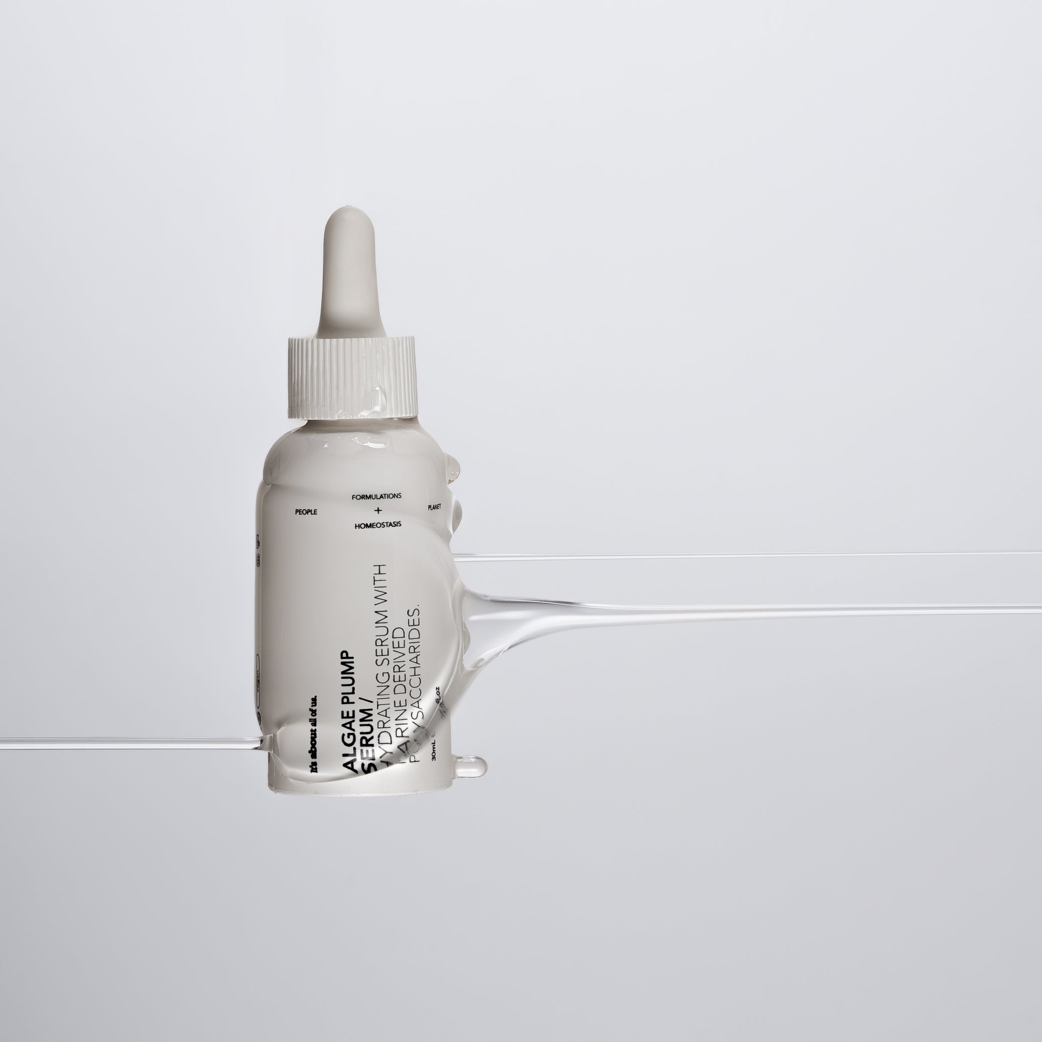 White serum bottle with dropper on a grey background, liquid dripping from left to right over the bottle
