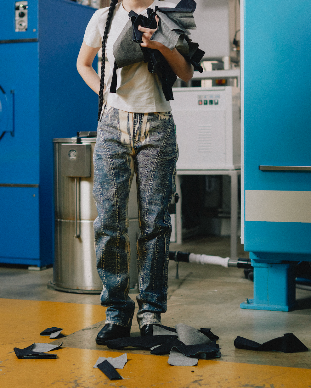 Person holding fabric in a workshop with blue walls and machinery.