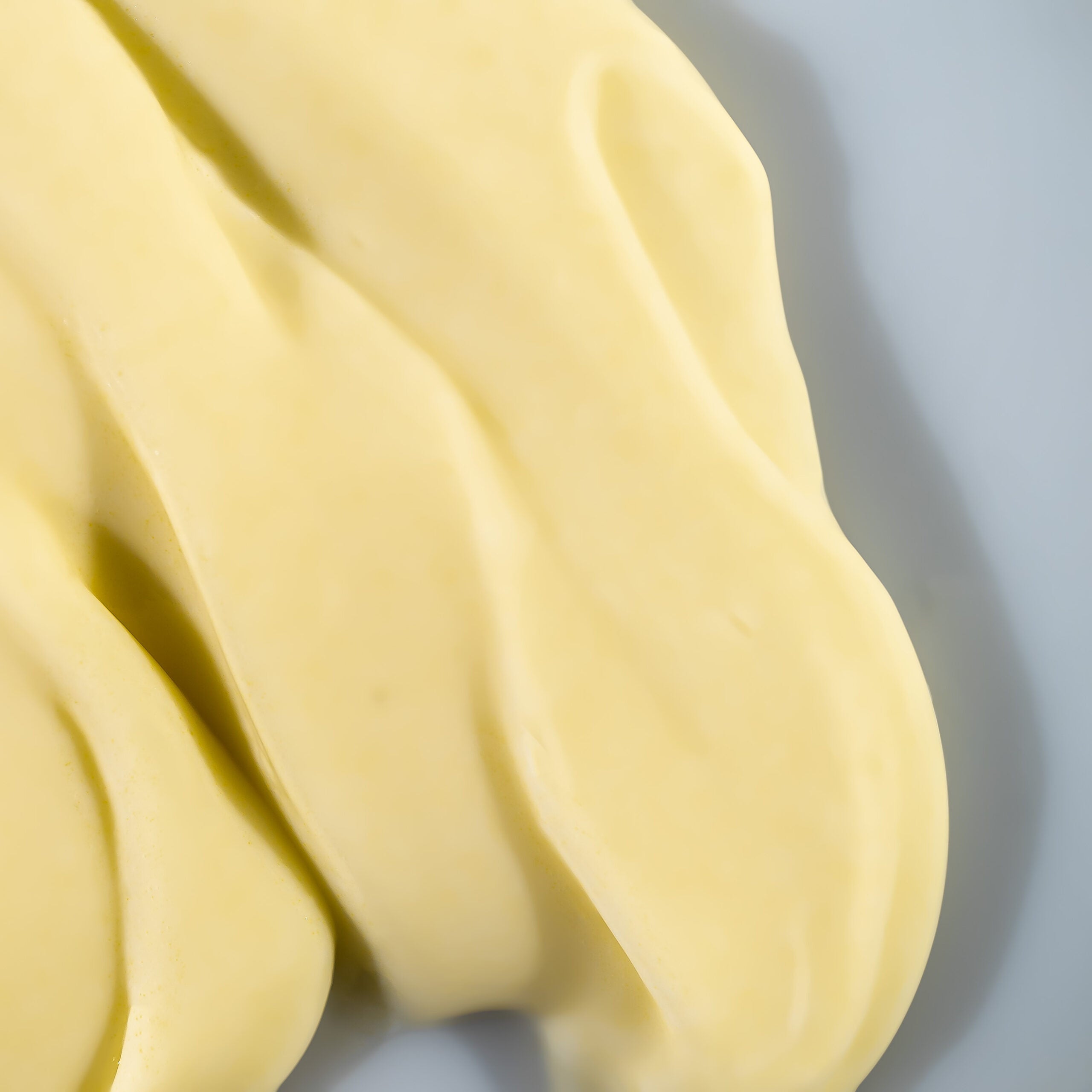 A close-up image of a yellow lotion on grey background