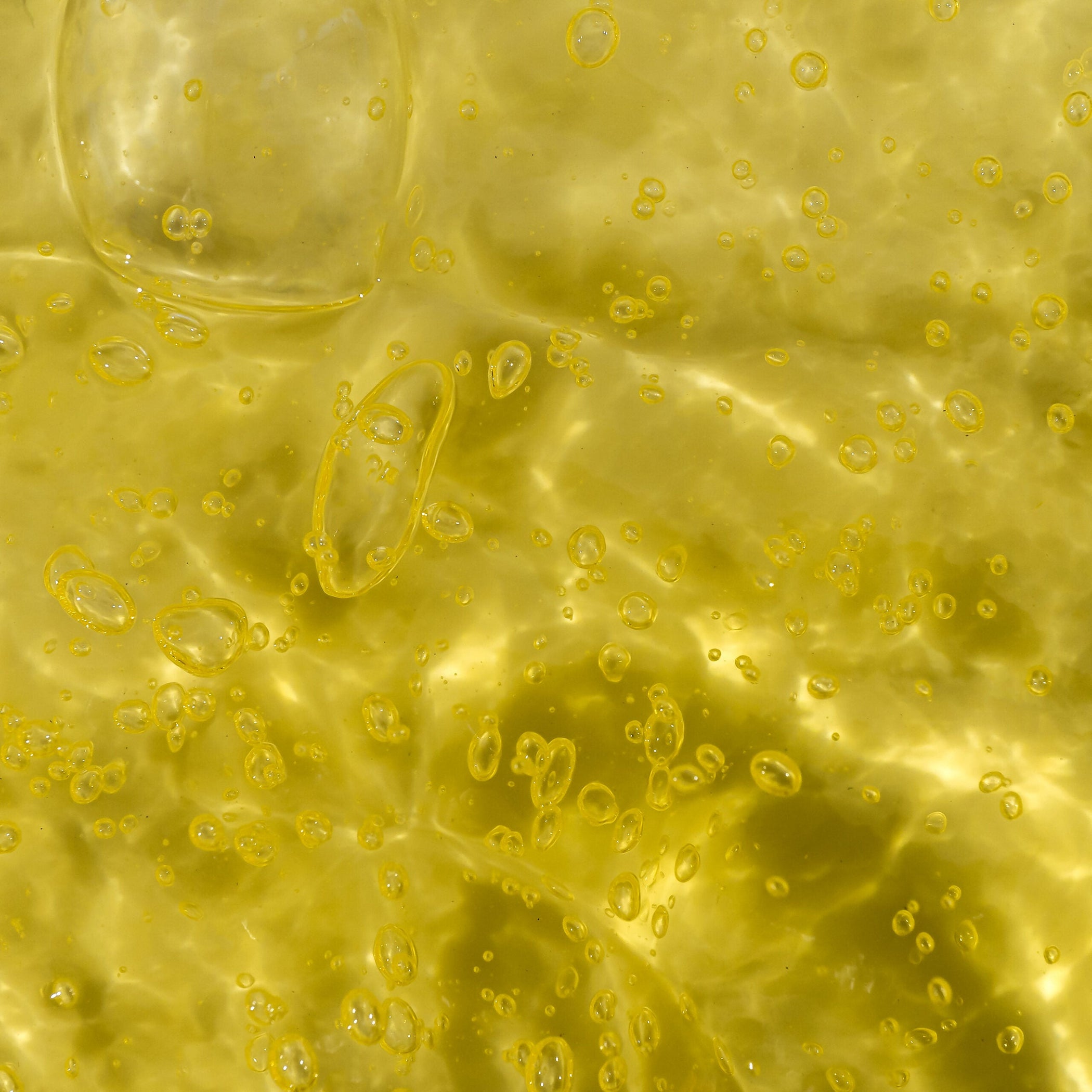 Close-up of a yellow gel liquid with visible bubbles, indicating a gel texture 