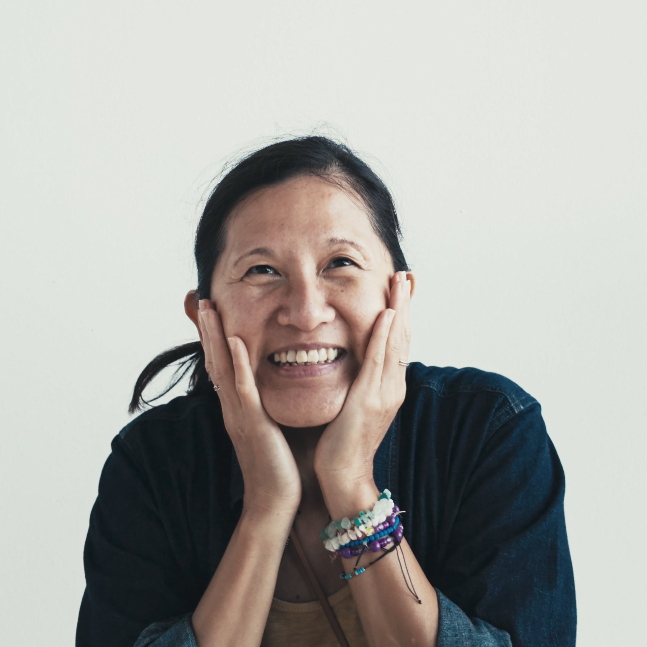 Model pressing both hands against face on plain background