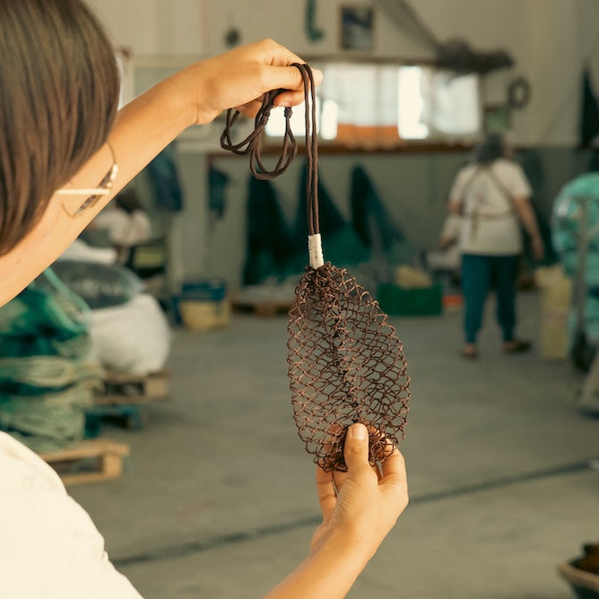 Person holding a woven bag in an indoor setting with blurred background